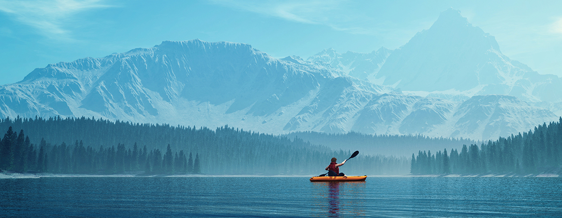 A kayaker paddles across a lake surrounded by snow-capped mountains