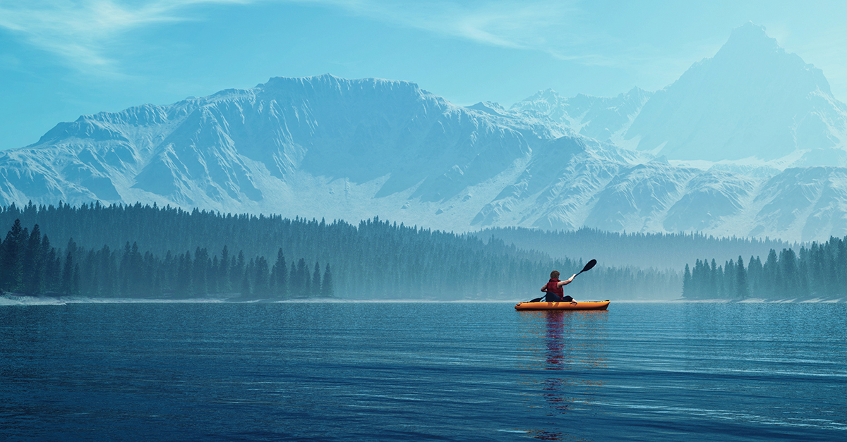 Man in a yellow canoe paddles in a lake surrounded by snow-capped mountains
