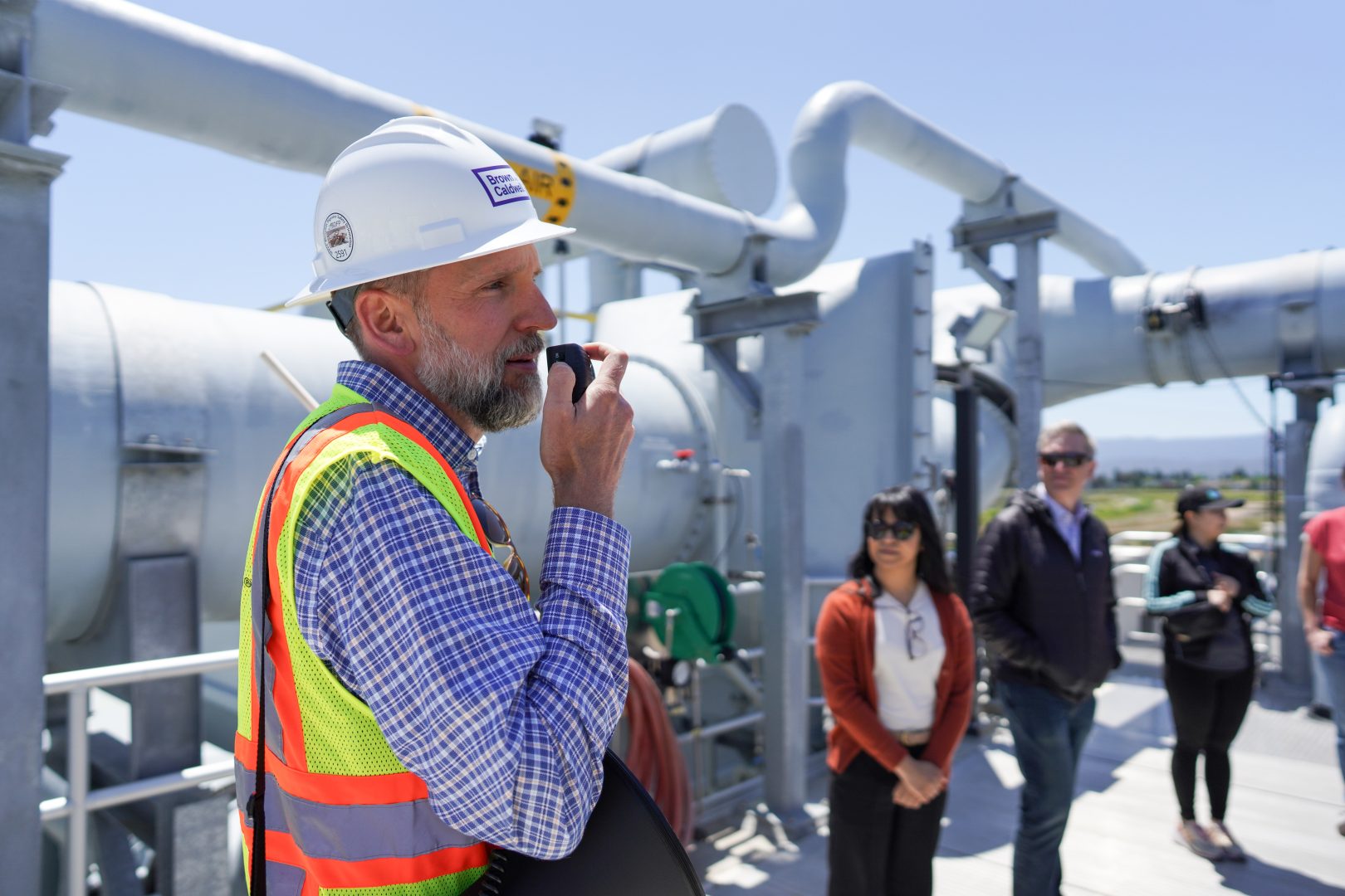 Aren Hansen, Brown and Caldwell Program Advisor, a man wearing a hardhat and safety vest, speaks at the Regional Environmental Sewer Conveyance Upgrade (RESCU) Program’s ribbon cutting at Silicon Valley Clean Water in May 2024.